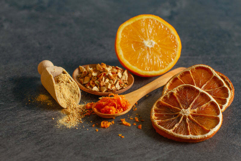 Orange, dried slice of oranges, and orange powder on a table